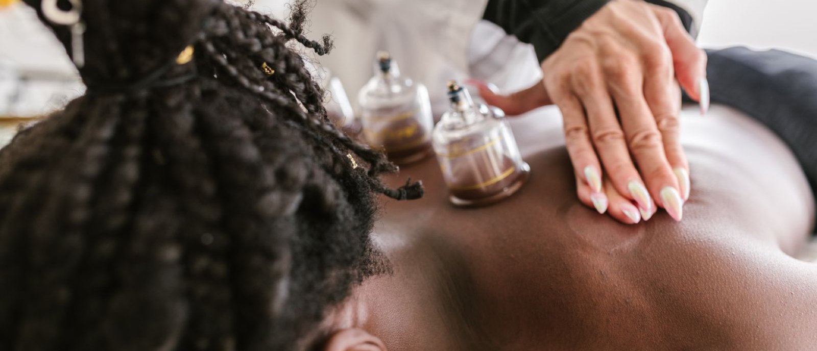 A therapist performing cupping therapy with glass cups on a client's back at Plum & Sugar