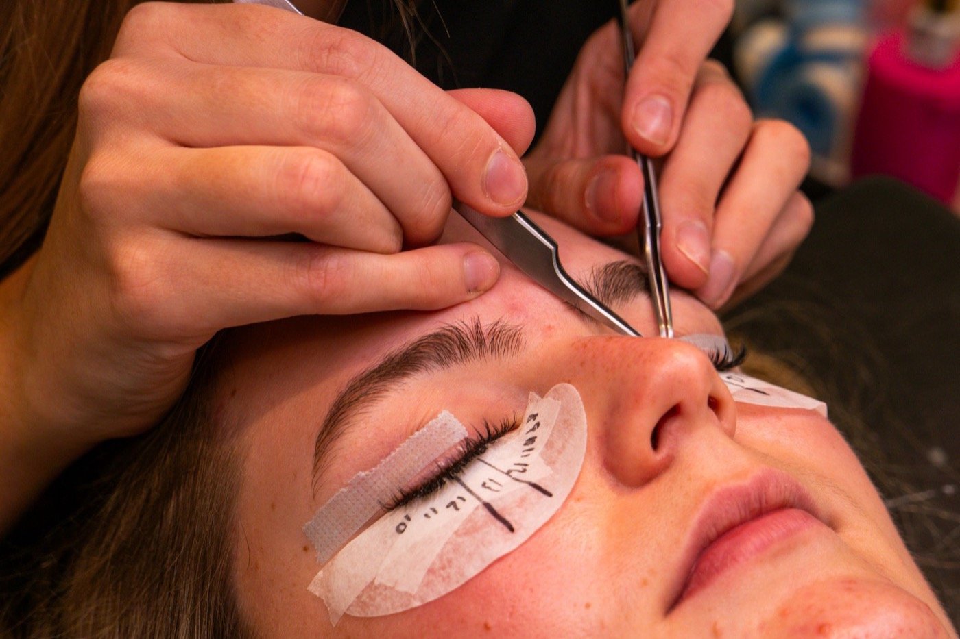 Close-up of a lash lift in progress with under-eye protection pads in place