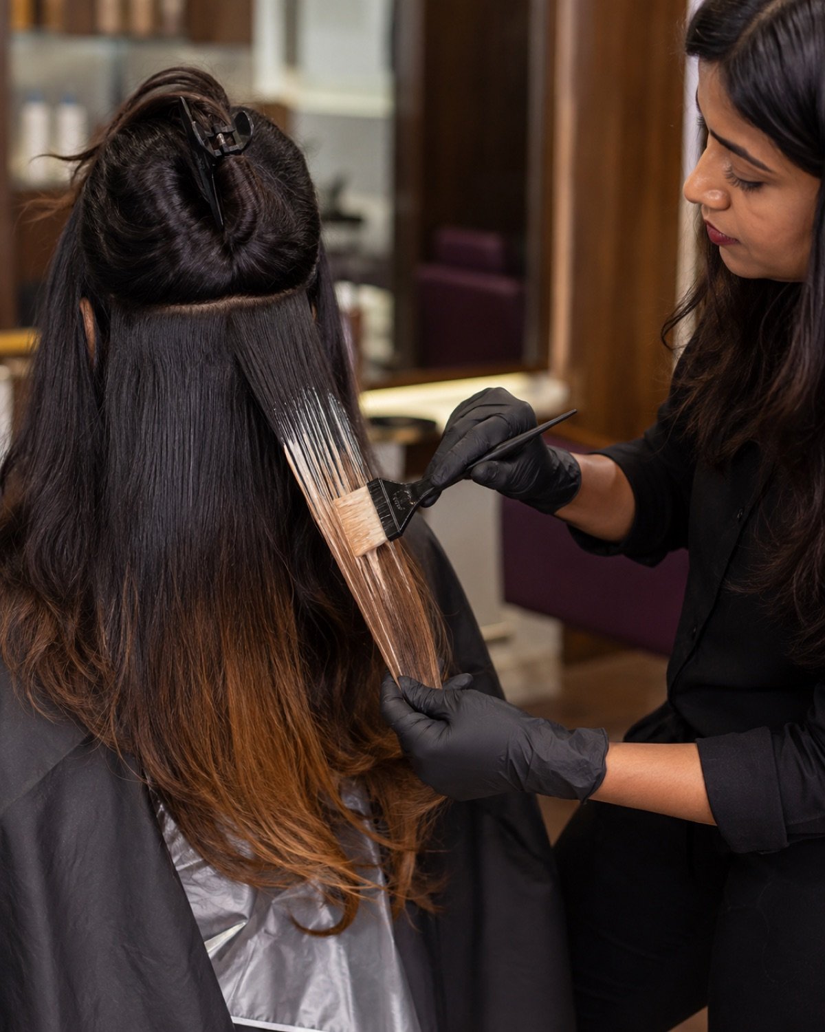 Colourist painting a soft ombre gradient through Indian hair