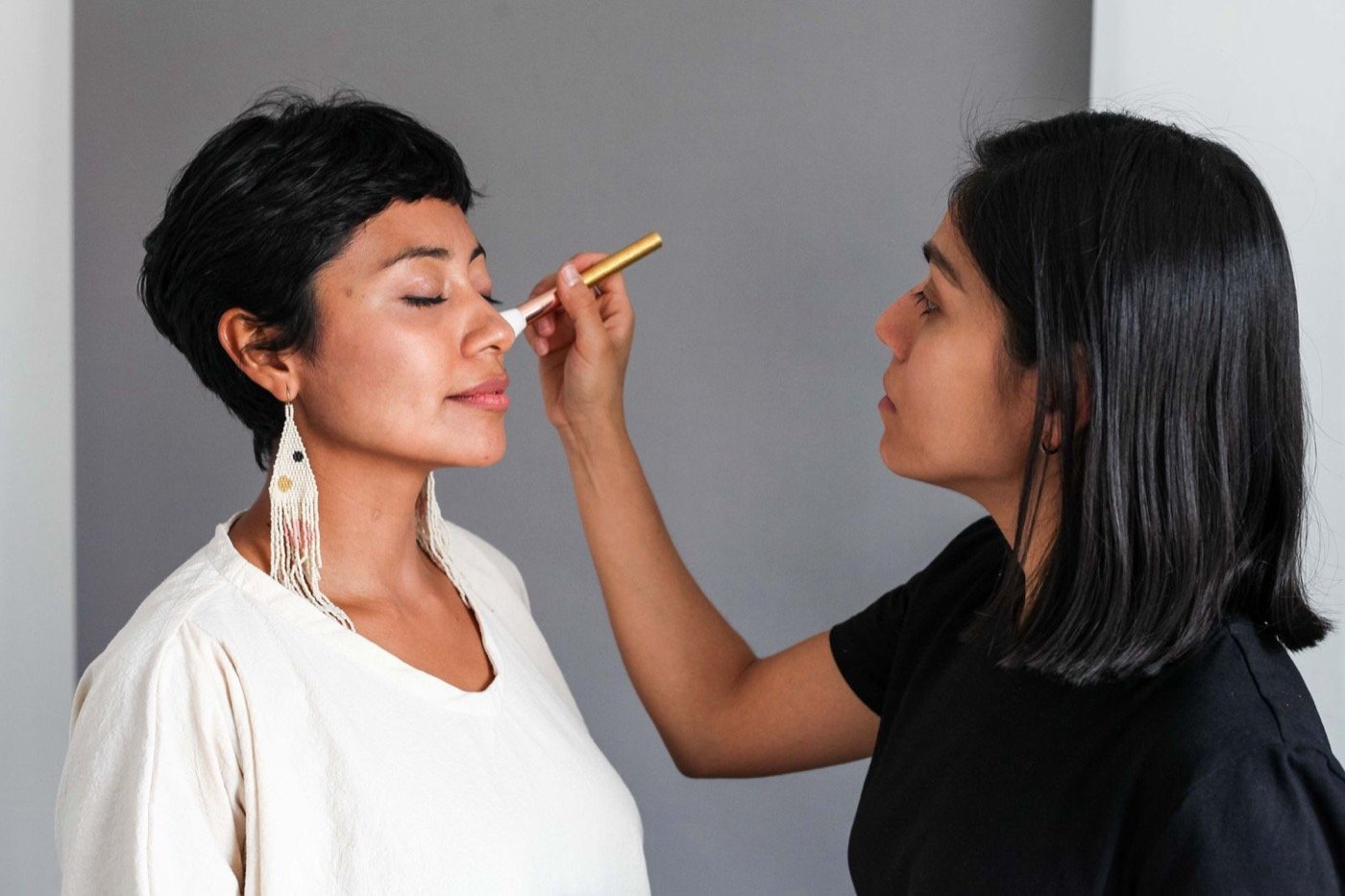 A makeup artist applying party makeup to a client at Plum & Sugar